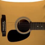 Uma almofada quadrada com uma estampa realista do corpo e das cordas de um violão sobre um fundo marrom-amarelado, perfeita para decoração musical e para dar um toque criativo a qualquer ambiente.