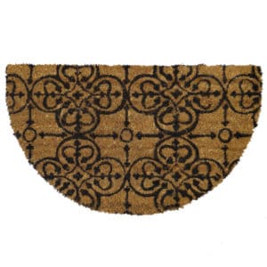 Um capacho marrom semicircular com um padr&atilde;o floral e geom&eacute;trico preto, sim&eacute;trico e ornamentado. O capacho tem uma superf&iacute;cie texturizada e o desenho se repete em toda a sua largura.