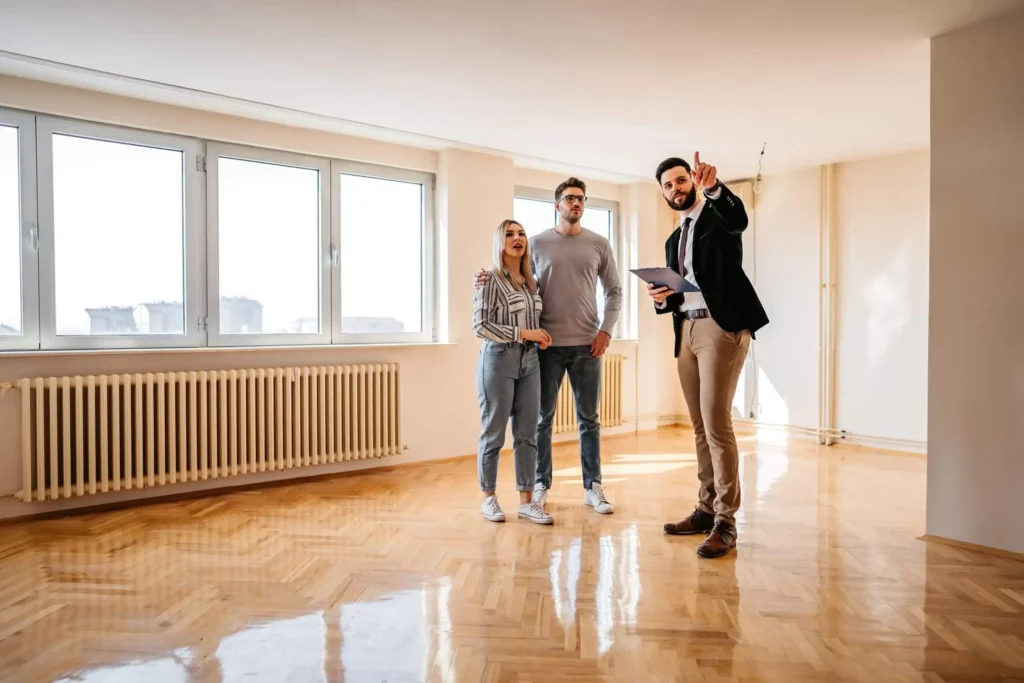 Imagem de um agente imobiliário mostrando um imóvel para um casal para ilustrar matéria sobre comprar ou alugar apartamento