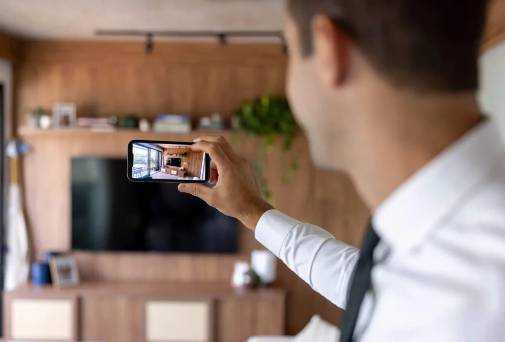 Imagem de um agente imobiliário tirando foto dos ambientes internos de uma casa para ilustrar matéria sobre como vender um imóvel com segurança