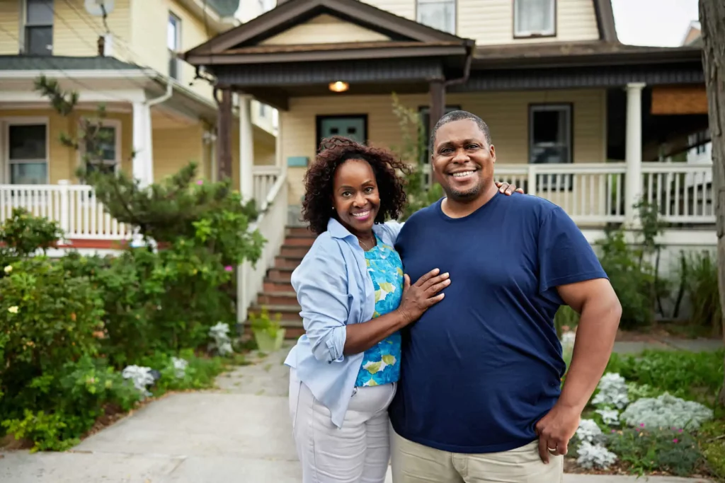 Imagem de um casal formado por um homem e uma mulher em frente a uma casa para ilustrar matéria sobre como vender um imóvel pelo QuintoAndar