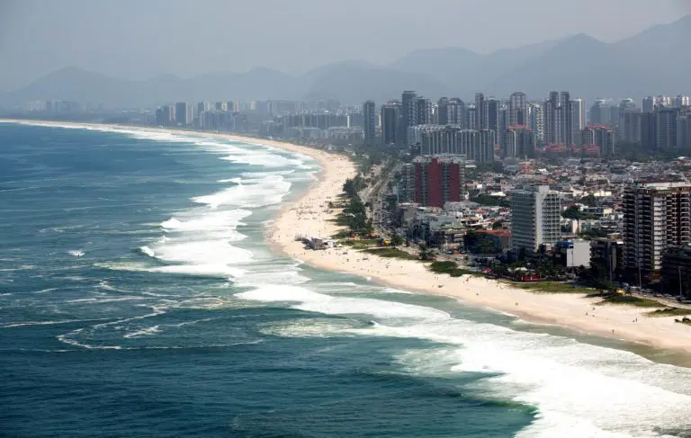 Imagem da vista da praia da Barra da Tijuca mostra mar, faixa de areia e prédios ao redor para ilustrar matéria sobre os bairros bons do RJ (Foto: Fernando Maia | Riotur)