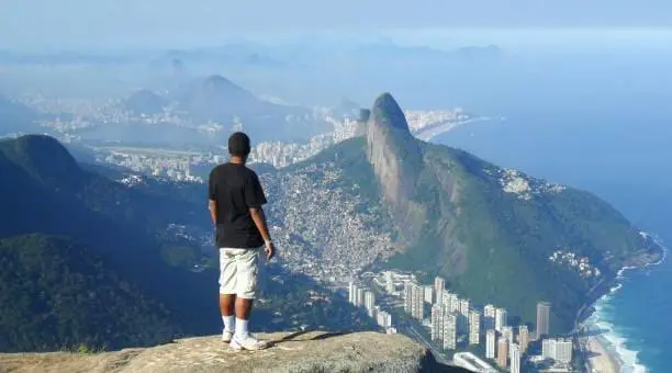 Imagem de um homem admirando a vista da Pedra da Gávea para ilustrar matéria sobre os bairros do Rio de Janeiro