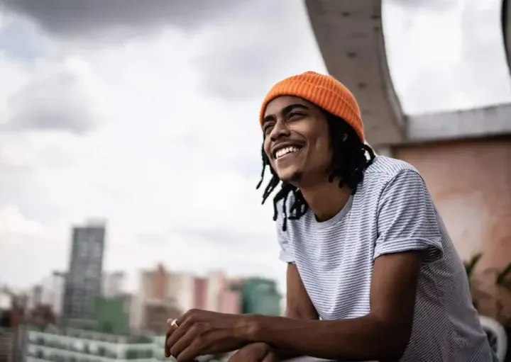 Imagem de um homem na varanda de um prédio observando a vista da cidade para ilustrar matéria sobre os bairros de São Paulo