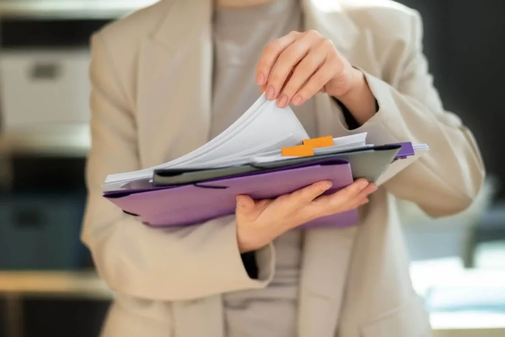 Imagem de uma mulher segurando pastas e documentos para ilustrar matéria sobre como comprar um apartamento na planta
