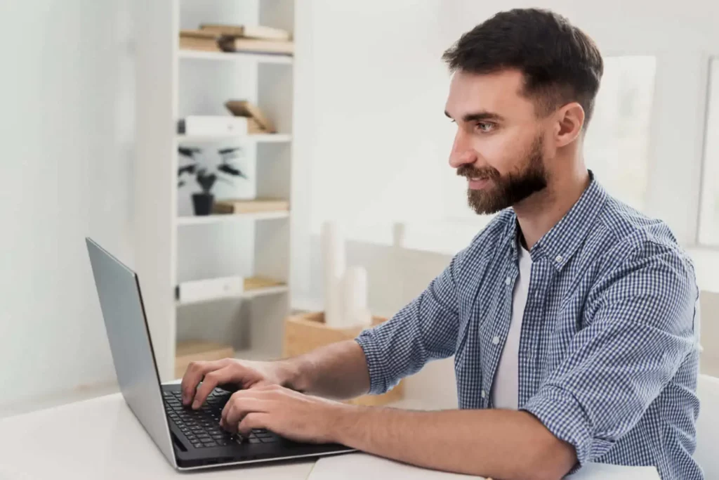 Imagem de um homem jovem com barba mexendo no computador para ilustrar matéria sobre como emitir certidão vintenária