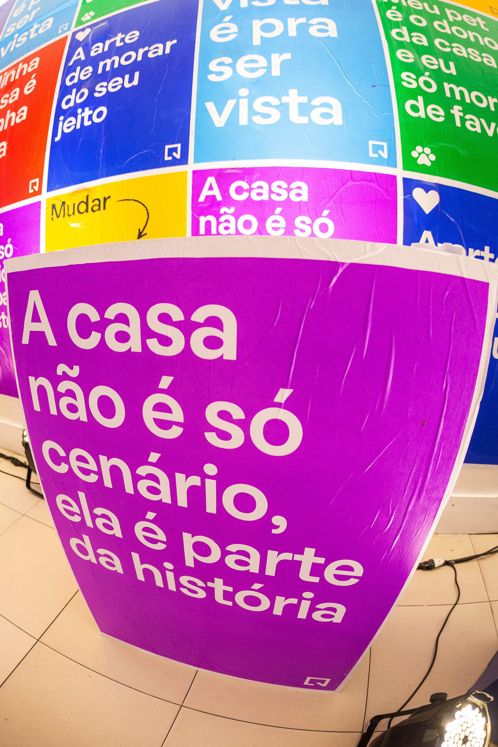 Foto que ilustra matéria sobre NaLata Festival mostra ação do QuintoAndar dentro da Casa NaLata com lambe-lambes coloridos com frases sobre o morar