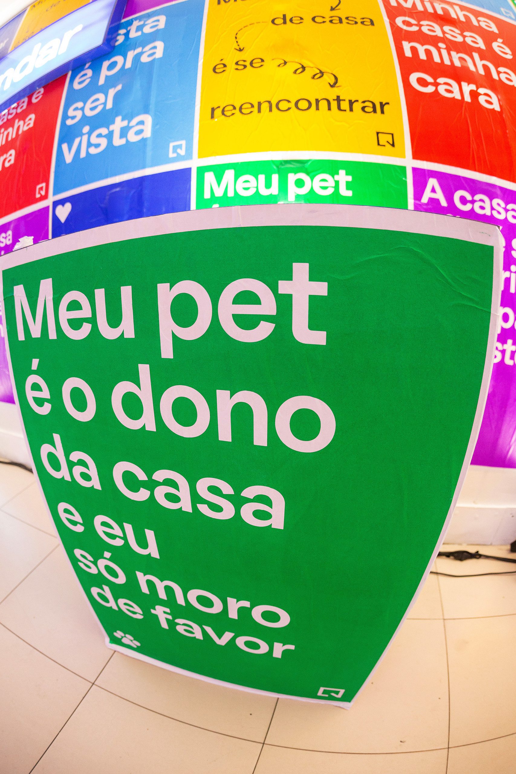 Foto que ilustra matéria sobre NaLata Festival mostra ação do QuintoAndar dentro da Casa NaLata com lambe-lambes coloridos com frases sobre o morar