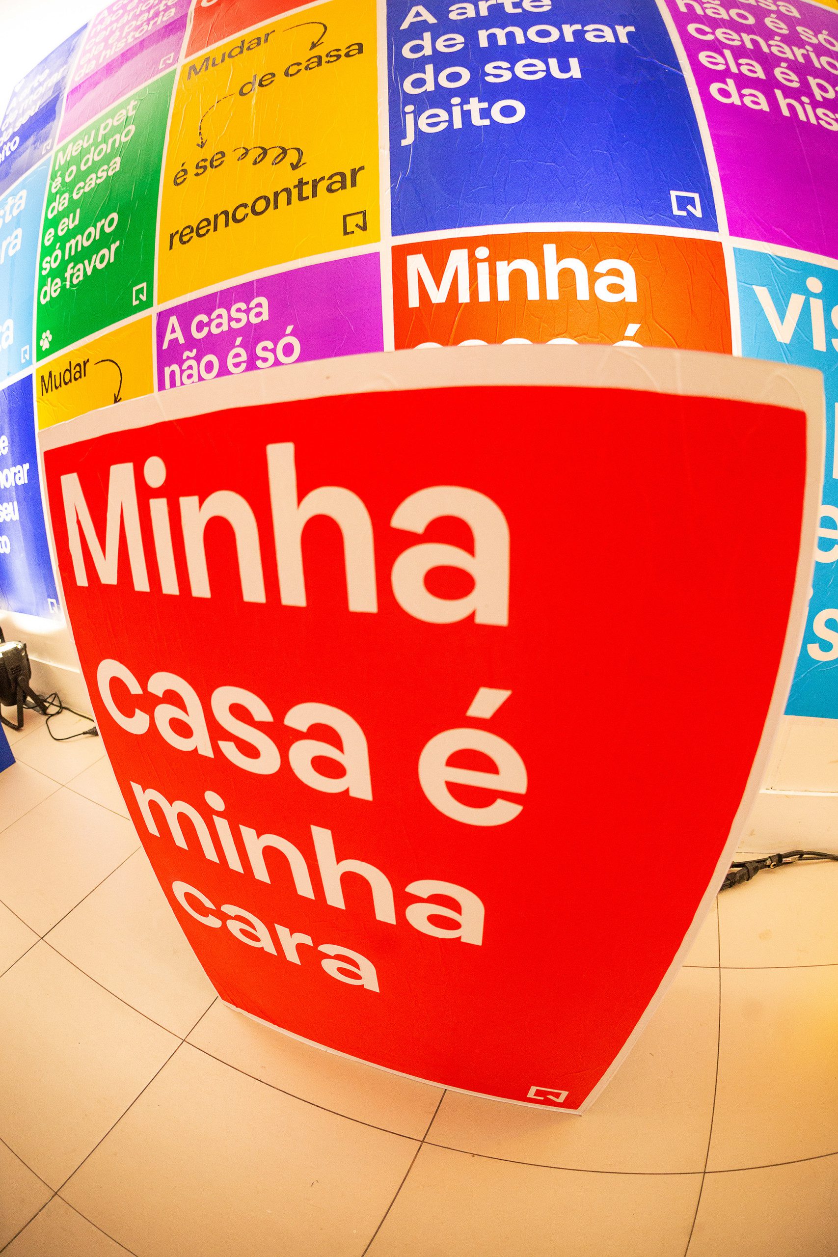 Foto que ilustra matéria sobre NaLata Festival mostra ação do QuintoAndar dentro da Casa NaLata com lambe-lambes coloridos com frases sobre o morar