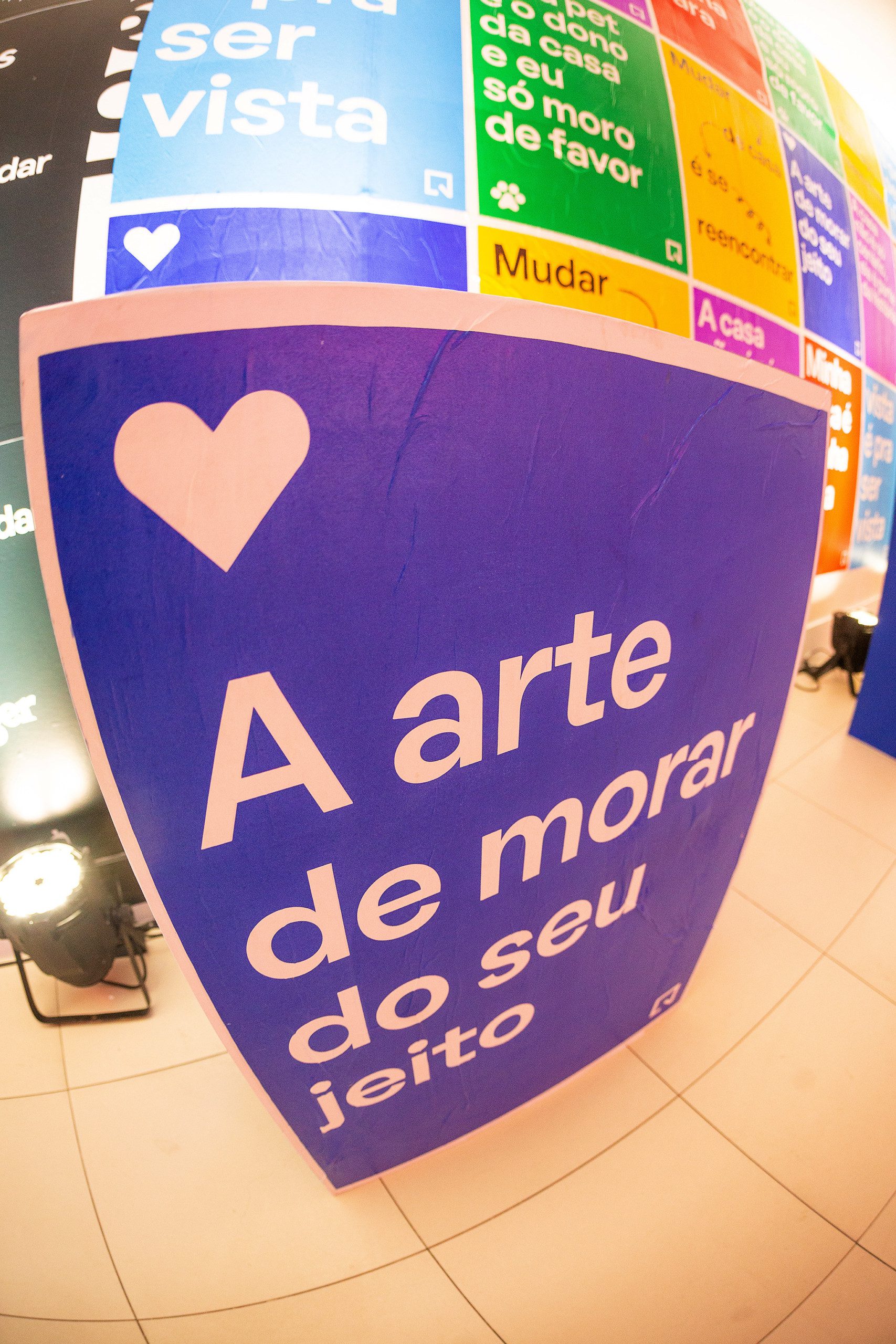 Foto que ilustra matéria sobre NaLata Festival mostra ação do QuintoAndar dentro da Casa NaLata com lambe-lambes coloridos com frases sobre o morar