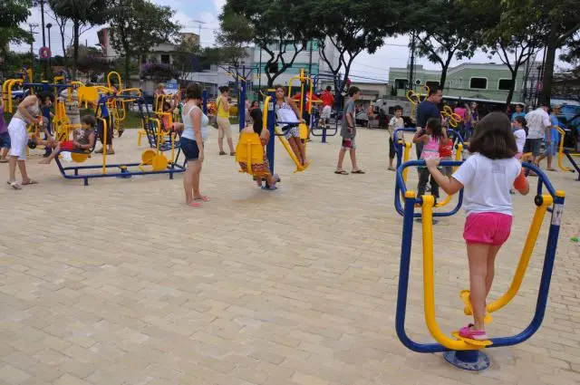Imagem de crianças e adultos utilizando equipamentos de ginástica na Praça Presidente Kennedy, no bairro Vila Bastos, em Santo André