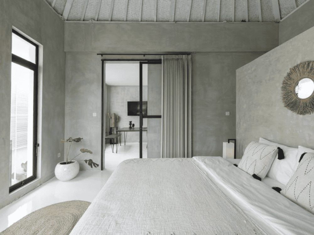 Quarto amplo com cama de casal king size e uma porta de correr de vidro ao fundo