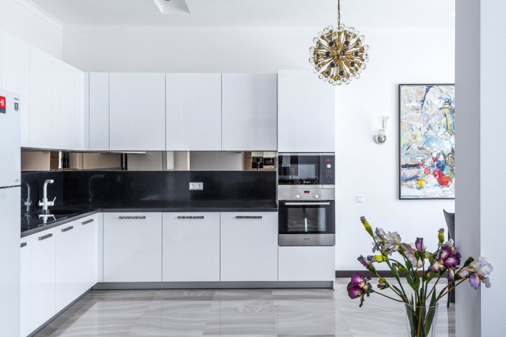Armário de cozinha branco com detalhes em preto com espaço para eletrodomésticos de embutir.