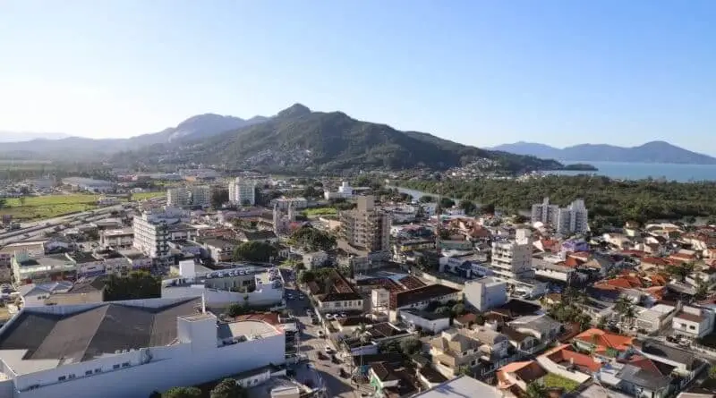 Imagem da vista aérea da cidade de Biguaçu, em Santa Catarina, mostra prédios, casas e vegetação ao fundo para ilustrar matéria sobre as melhores cidades de Santa Catarina para morar