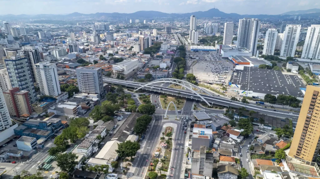 Imagem da vista aérea de Osasco mostra a Ponte Metálica, Viaduto reinaldo de Oliveira, avenidas, prédios, montanhas ao fundo e vegetação do município para ilustrar matéria sobre as escolas municipais em Osasco