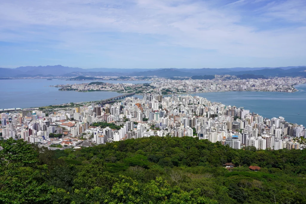 Imagem da paisagem urbana de Florianópolis, capital de Santa Catarina, mostra vegetação, prédios e o mar