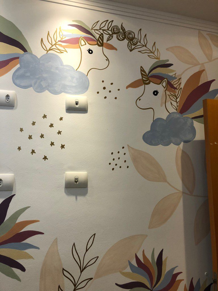 Parede de um quarto infantil com desenhos de unicórnios feitos à mão.