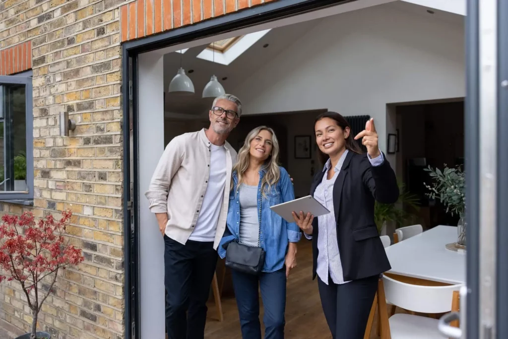 Imagem de um casal formado por um homem e uma mulher visitando um imóvel ao lado de uma corretora imobiliária para ilustrar matéria sobre o que é carta de crédito