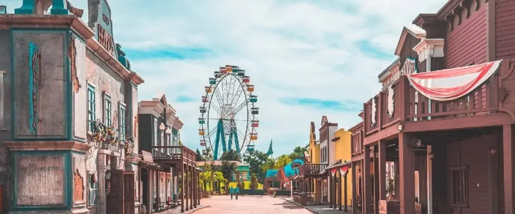 Imagem do Hopi Hari mostra edifícios coloridos em ambos os lados e uma grande roda-gigante ao fundo, para ilustrar matéria sobre o que tem para fazer em Vinhedo