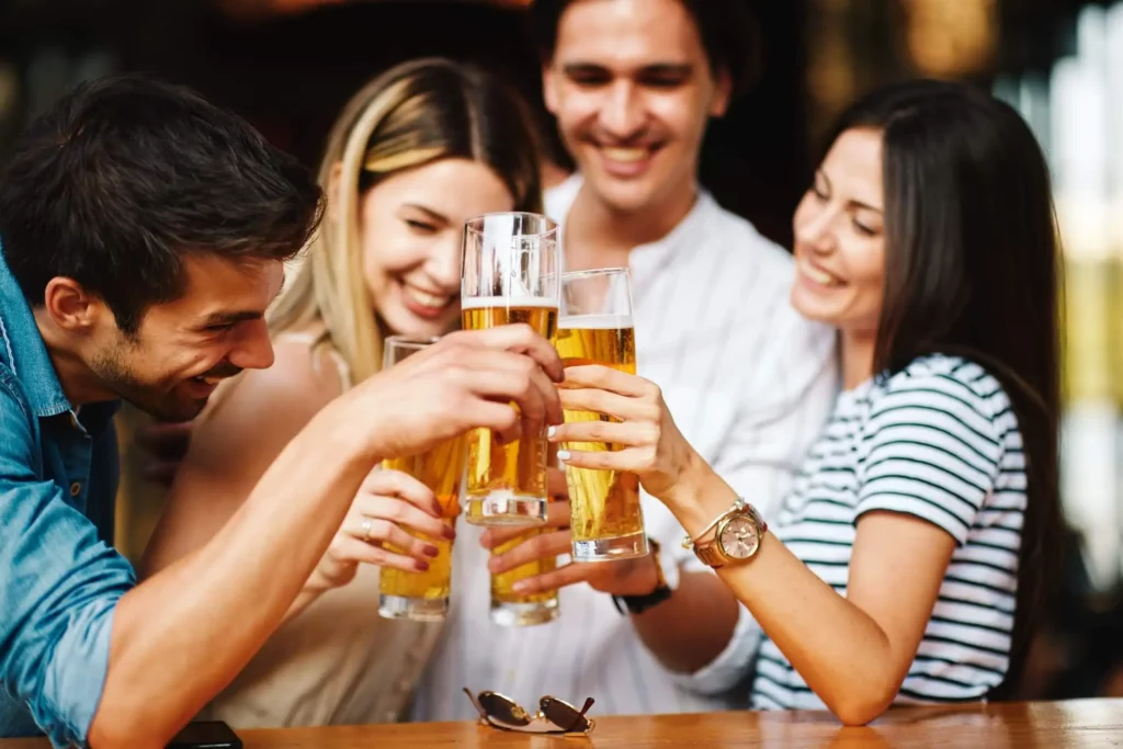 Imagem de amigos brincando com copos de cerveja para ilustrar matéria sobre restaurantes e lojas do Mercado Novo BH