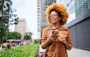 Imagem de uma mulher andando pela Avenida Paulista com o celular na mão para ilustrar matéria sobre o custo de vida em São Paulo