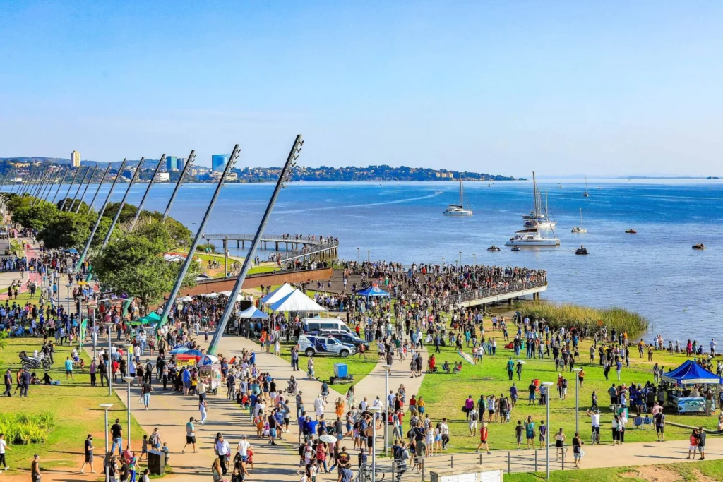 Imagem de pessoas reunidas no calçadão da Orla do Guaíba, em Porto Alegre, em um dia de céu azul, para ilustrar matéria sobre o que fazer em Porto Alegre com crianças