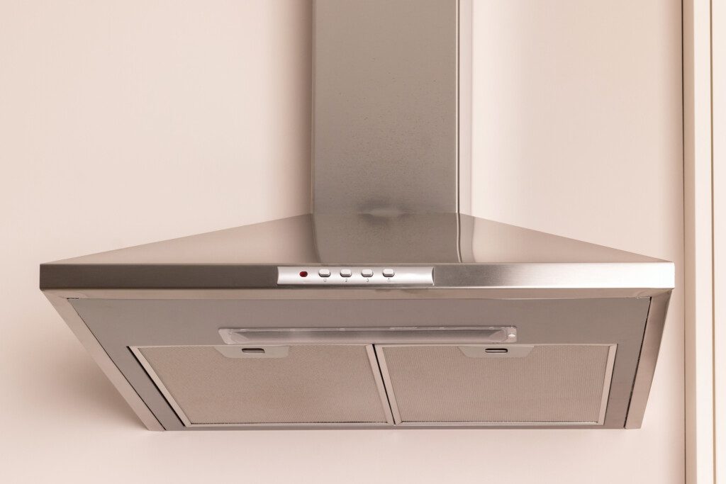 Imagem de uma coifa de inox instalada em uma parede de tom claro