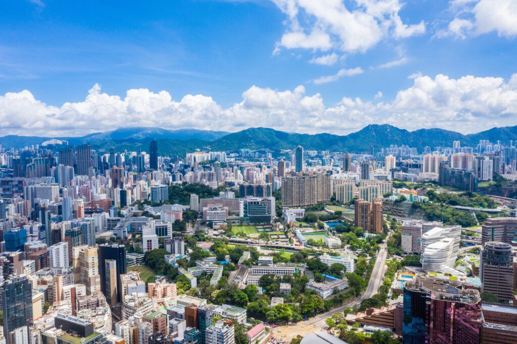 Imagem panorâmica de um bairro com vista para os prédios altos, montanhas e áreas arborizadas da região