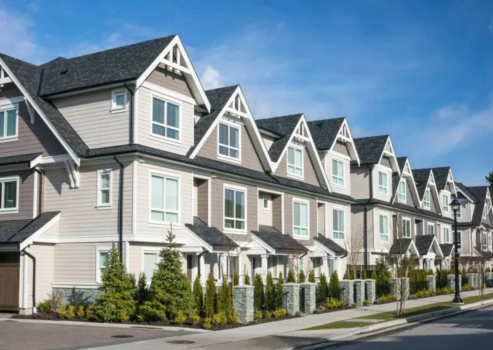 Imagem de um condomínio de townhouses modernas com fachada na cor branca com detalhes marrons para ilustrar matéria sobre o que significa uma townhouse