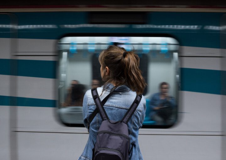 Vista traseira de uma mulher de costas com uma mochila nas costas esperando o metrô na estação para ilustrar matéria sobre a linha 6, do metrô de São Paulo