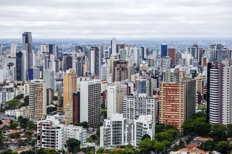 Imagem da vista aérea de Curitiba mostra prédios da cidade para ilustrar matéria sobre os bairros bons e baratos para morar em Curitiba