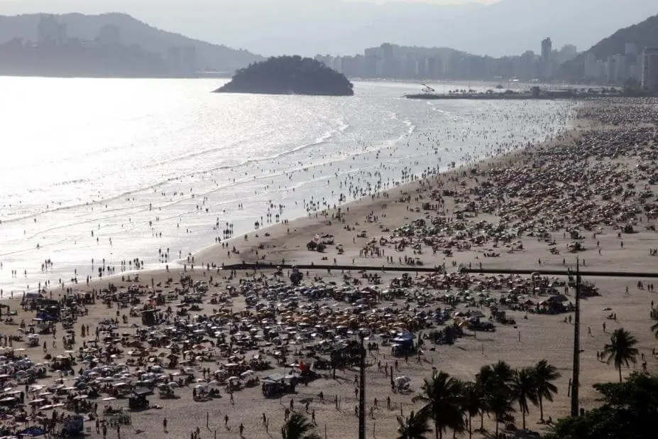 Imagem de uma praia em Santos com banhistas na faixa de areia para ilustrar matéria sobre o custo de vida em Santos