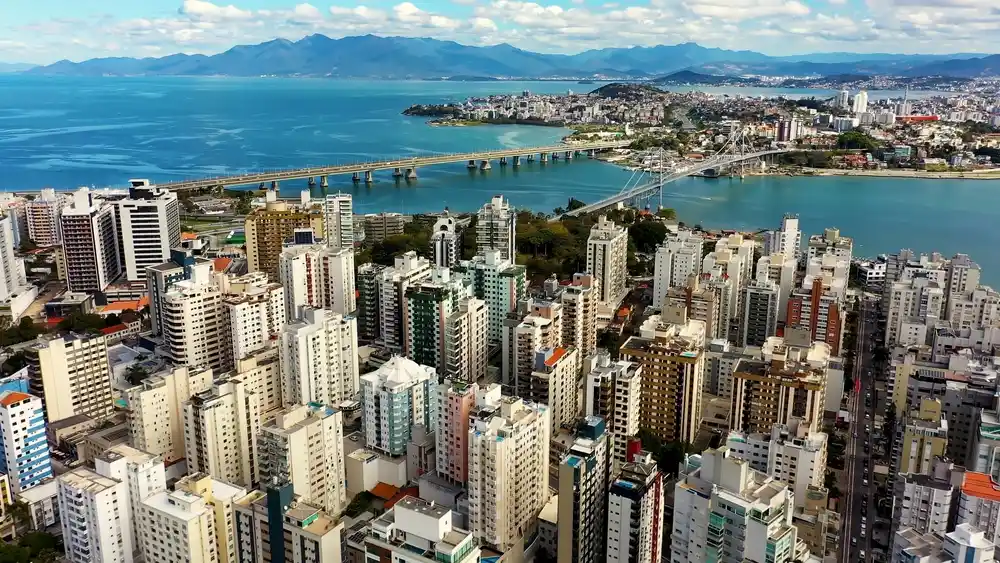 Imagem da vista aérea de Florianópolis mostra prédios, ponte e vegetação da ilha para ilustrar matéria sobre as cidades brasileiras mais visitadas