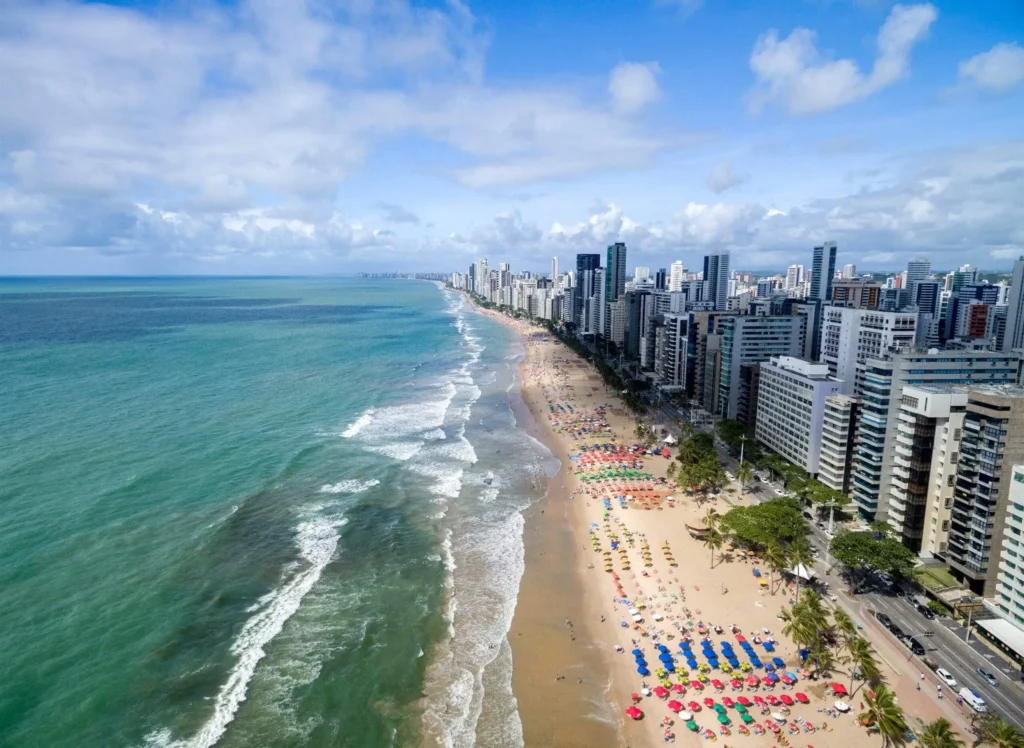 Imagem da vista aérea da Praia de Boa Viagem, em Recife, mostra orla, prédios, mar e turistas na areia para ilustrar matéria sobre as cidades do Brasil visitadas