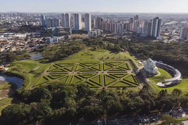 Imagem da vista aérea do gramado do Jardim Botânico de Curitiba com prédios ao fundo para ilustrar matéria sobre quais as cidades mais desenvolvidas do Brasil