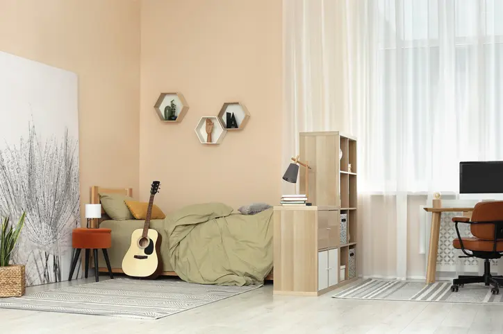 Foto de um quarto juvenil bege com um violão ao lado da cama.