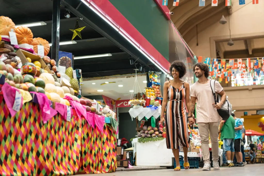 Imagem de um casal andando pelas lojas do Mercado Municipal de São Paulo para ilustrar matéria sobre a Linha 1-Azul do metrô de SP