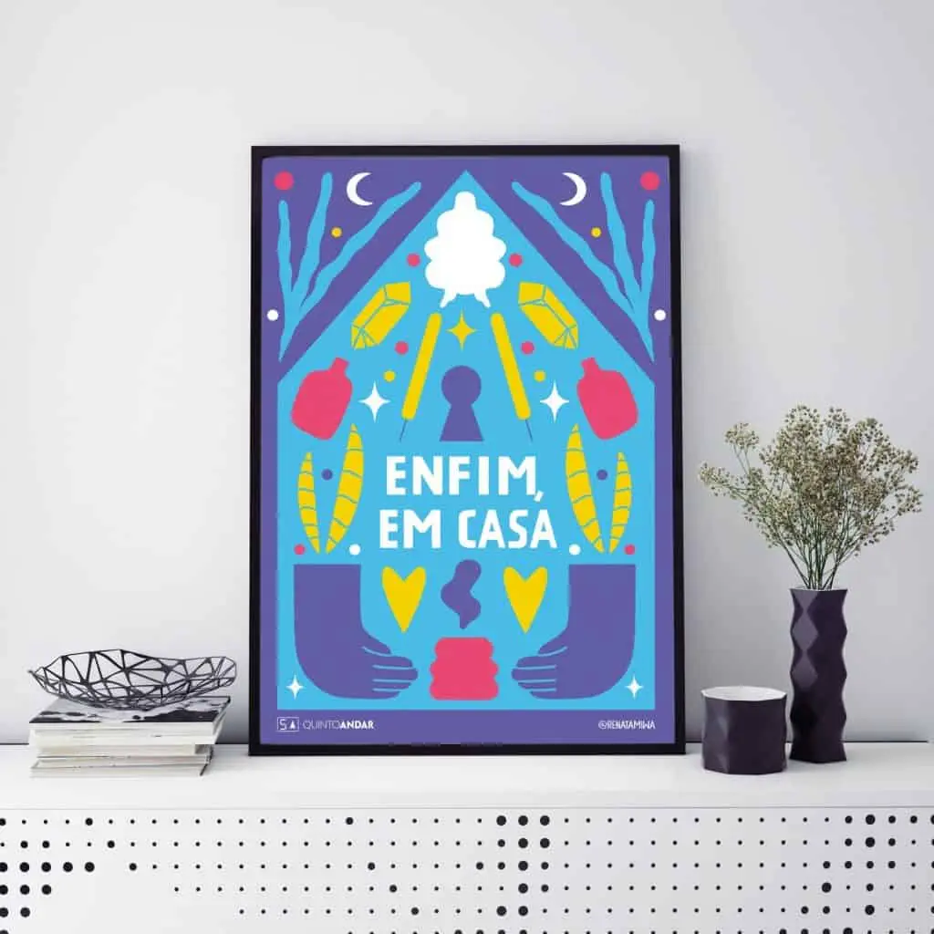 Uma obra de arte colorida emoldurada do QuintoAndar Colab com as palavras em português Enfim, em casa fica em uma prateleira branca, cercada por formas abstratas, corações, penas e decoração como uma tigela e uma pequena planta em um vaso escuro.