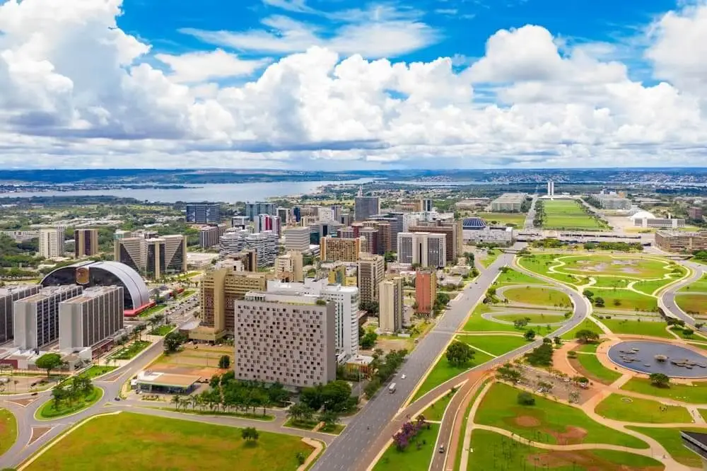 Imagem aérea com vista para prédios comerciais, lago paranoá e Congresso Nacional, em Brasília