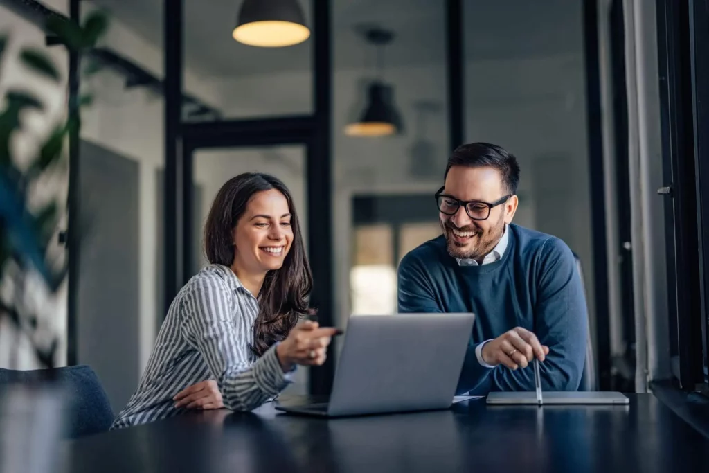 Imagem de um homem e uma mulher em uma sala de reuniões em um escritório empresarial olhando para a tela de um notebook para ilustrar matéria sobre a Dimob para aluguel