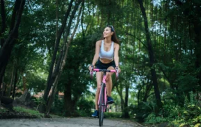 Imagem panorâmica de uma mulher jovem andando de bicicleta em um parque para ilustrar matéria sobre parque para andar de bicicleta em SP