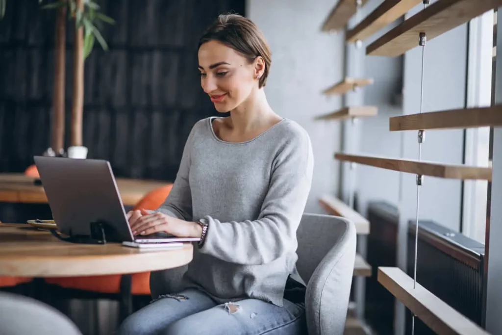 Imagem de uma mulher sorridente mexendo no computador para ilustrar matéria sobre quanto vou pagar no financiamento de um imóvel de R$ 400 mil