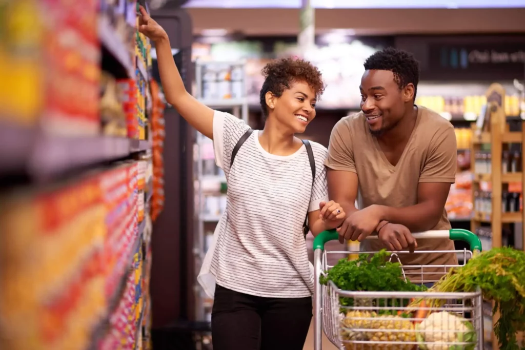 Imagem de um casal formado por um homem e uma mulher fazendo compras em um mercado para ilustrar matéria sobre bairro comercial, exemplo
