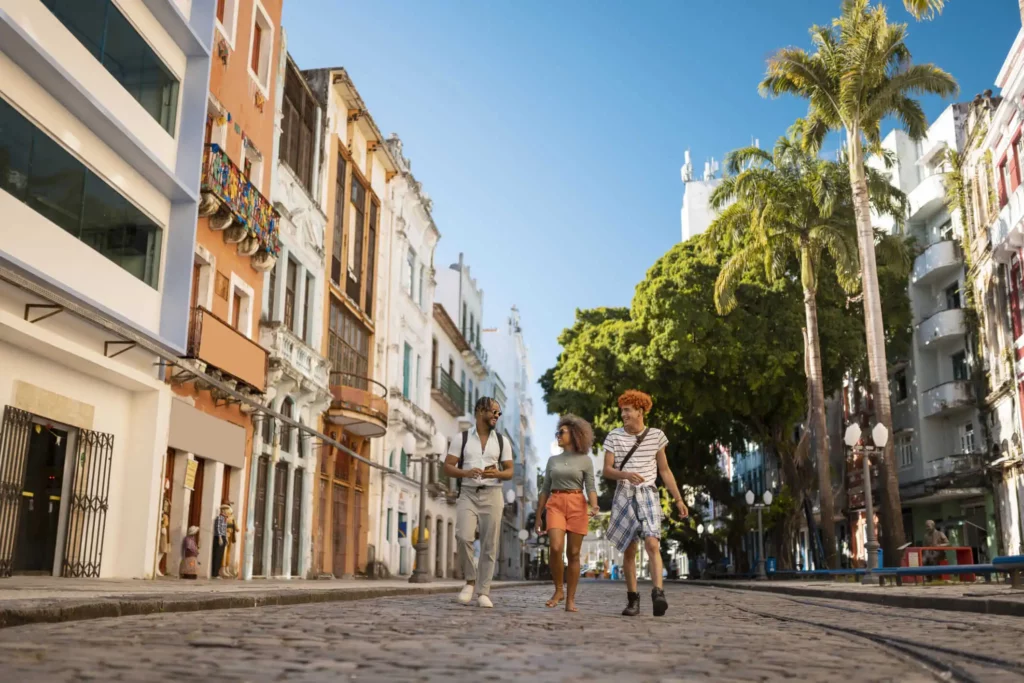 Imagem de três pessoas andando em uma avenida para ilustrar matéria sobre a diferença entre bairro comercial, industrial e residencial