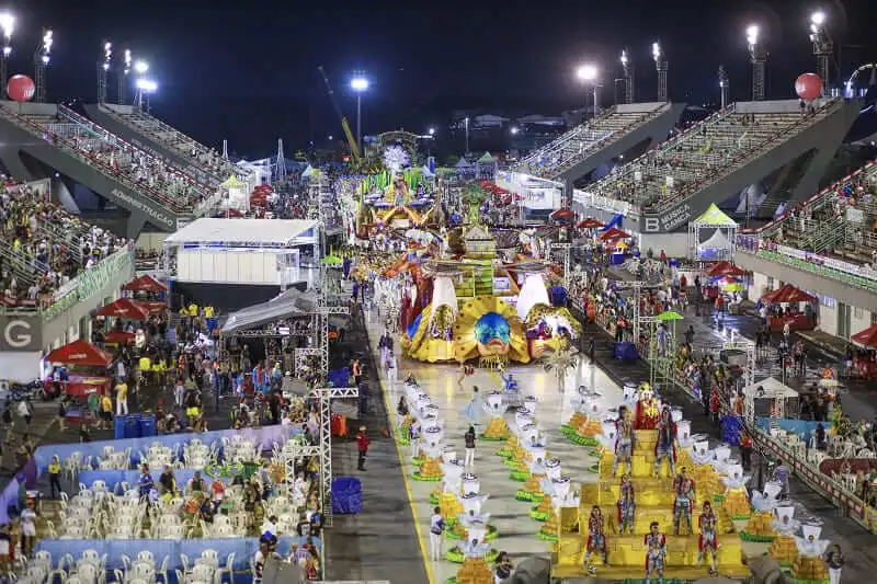 Imagem do sambódromo de Manaus mostra desfile de carnaval, carros alegóricos no centro da passarela e público nas arquibancadas para ilustrar matéria sobre as melhores cidades para ir para o carnaval