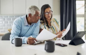 Imagem que ilustra matéria sobre mudanças no imposto de renda 2025 mostra um casal vendo papéis em cima de uma mesa e com feição de pensativos