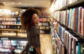 Imagem de uma mulher olhando livros em uma prateleira em uma livraria para ilustrar matéria sobre as livrarias em SP