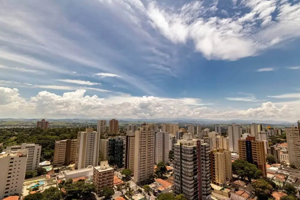 Foto que ilustra matéria sobre as melhores cidades para morar e trabalhar em São Paulo mostra uma visão do alto da cidade, onde aparecem grandes prédios. Ao fundo, um céu azul com algumas poucas nuvens brancas