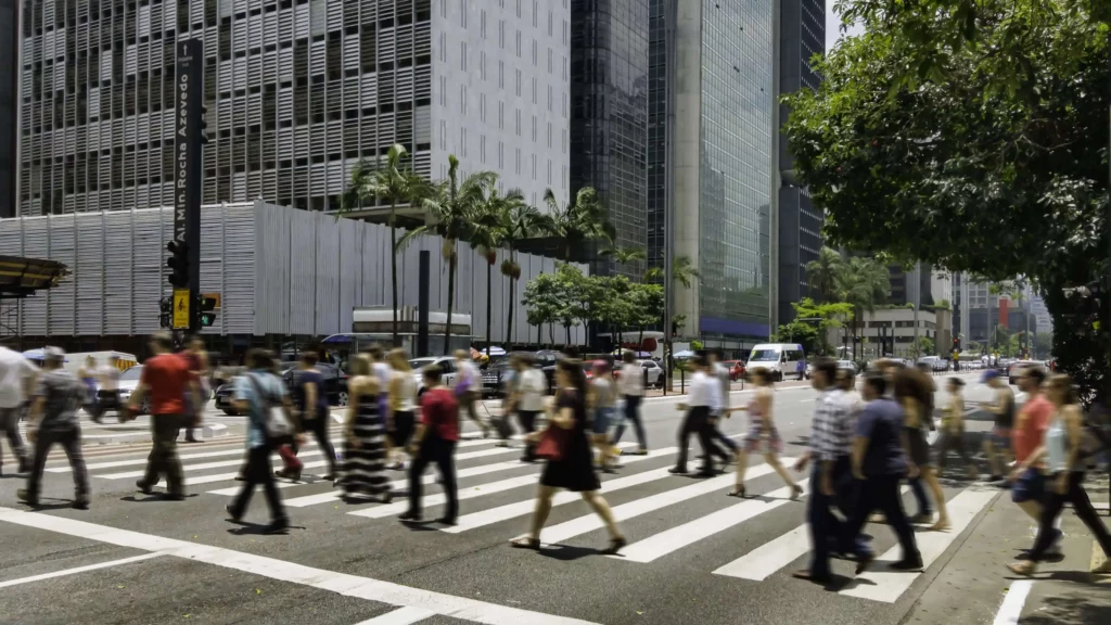 Imagem de pessoas atravessando uma faixa de pedestres na Avenida Paulista, em São Paulo, para ilustrar matéria sobre o que é o plano diretor e qual sua importância