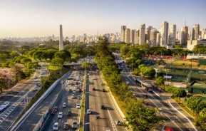 Imagem da Avenida 23 de Maio, em São Paulo, mostra vista aérea da cidade com avenidas, carros, obelisco, vegetação e prédios ao fundo para ilustrar matéria sobre o plano diretor